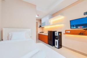 タンゲランにあるNice and Simply Look Studio Apartment at B Residence By Travelioのベッドルーム1室(ベッド1台付)、キッチン(テレビ付)