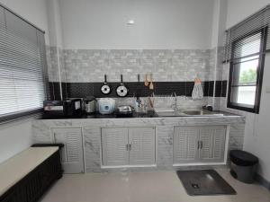 a kitchen with white cabinets and a sink and a window at We house หางดง 2 in Ban Pa Mak (1)