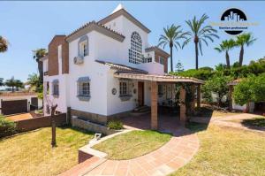 a large white house with palm trees in the background at Villa del Mar in Torremolinos