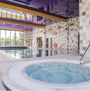 un grand jacuzzi dans une pièce avec une grande fenêtre dans l'établissement Apartamenty Wybrzeże Laguna Perła 5 Mórz Basen & SPA, SAT DE i EN, à Ustronie Morskie