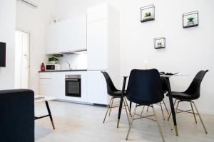 Una cocina blanca con sillas y mesa negras. en Pavia - Esclusivo appartamento in pieno centro, en Pavia