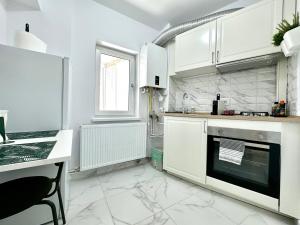 a white kitchen with white cabinets and a window at Park View Studio in Timişoara