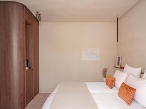 a bedroom with a bed with white sheets and orange pillows at Hôtel Liautaud Rooftop Cassis in Cassis