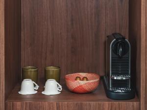 a coffee maker on a wooden shelf with cups and a bowl at Hôtel Liautaud Rooftop Cassis in Cassis