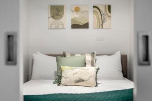 a bedroom with a bed with white pillows and paintings at Serene Two Bedroom Apartment in Melbourne CBD with Free Parking in Melbourne +9 photos