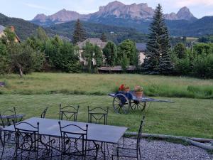 grupa stołów i krzeseł na polu z górami w obiekcie Maison dans parc clôturé w mieście Barcelonnette