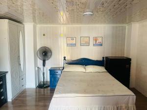 a bedroom with a bed with a blue headboard and a fan at Cozy House in Rose Hill