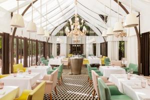 a restaurant with white tables and chairs and a chandelier at Hôtel Le Royal Monceau Raffles Paris in Paris