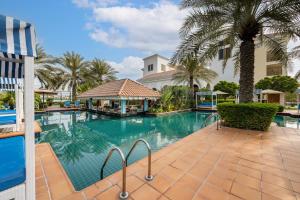 une piscine avec des palmiers et un bâtiment dans l'établissement Al Habtoor Polo Resort, à Dubaï