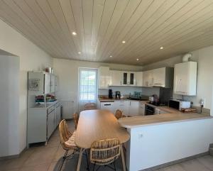 a large kitchen with a wooden table and chairs at Villa Vendée EU in Saint-Michel-en-lʼHerm