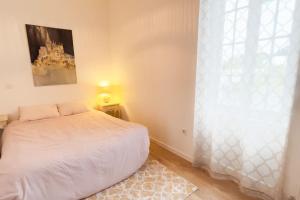 a bedroom with a white bed and a window at Villa Vendée EU in Saint-Michel-en-lʼHerm