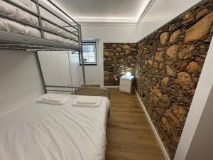 a bedroom with a bunk bed and a stone wall at XperienceHouse Janeiro in Janeiro de Cima +24 photos
