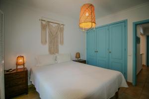 a bedroom with a white bed and a blue door at FLH Praia Verde Rooftop House in Praia Verde