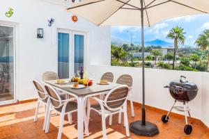 a table with chairs and an umbrella and a grill at Tetuan 15 - Oasis Properties in Nerja
