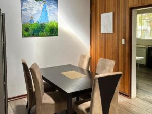 a dining room table with chairs and a painting on the wall at Royal Bafokeng Guest House in Bloemfontein
