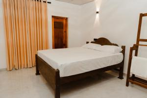 a bedroom with a bed with white sheets at Heritage Eco Garden in Dickwella