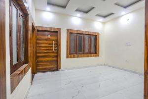 an empty room with a wooden door and a window at FabHotel Imperail House in Prayagraj