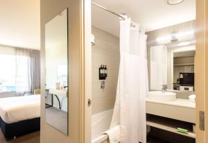 a bathroom with a tub and a sink and a mirror at Sudima Auckland Airport in Auckland