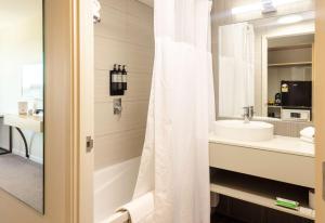 a bathroom with a white shower curtain and a sink at Sudima Auckland Airport in Auckland