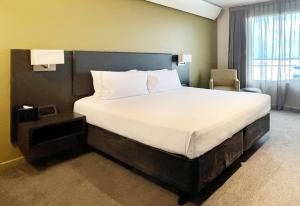 a bed in a hotel room with a large white bed at Sudima Auckland Airport in Auckland