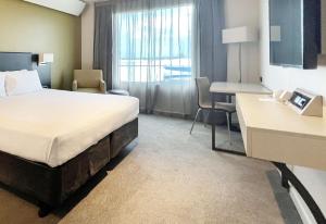 a hotel room with a bed and a desk at Sudima Auckland Airport in Auckland