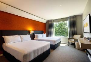 a hotel room with two beds and a window at Sudima Auckland Airport in Auckland