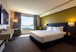 a hotel room with a bed and a large window at Sudima Auckland Airport in Auckland