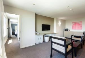 a living room with a television and a table and chairs at Sudima Auckland Airport in Auckland