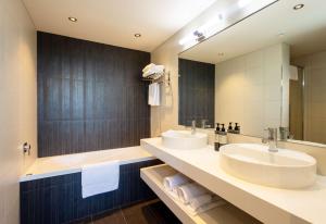 a bathroom with two sinks and a large mirror at Sudima Auckland Airport in Auckland