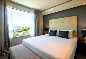 a bedroom with a large bed with a large window at Sudima Auckland Airport in Auckland