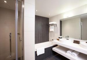 a bathroom with two sinks and a mirror at Sudima Auckland Airport in Auckland