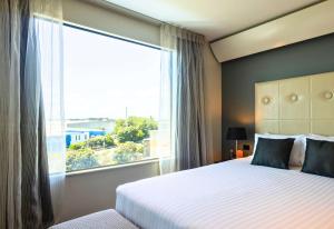 a bedroom with a bed and a large window at Sudima Auckland Airport in Auckland