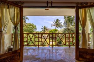 Una puerta abierta a un balcón con vista a las palmeras. en Diani Beach - Villa Mashariki - Private Villa, en Diani Beach