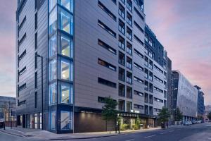 ein hohes Gebäude in einer Stadtstraße in der Unterkunft The Reach at Piccadilly, Manchester, a Tribute Portfolio Hotel in Manchester