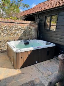 a large jacuzzi tub sitting outside of a house at Kings Barn - English Countryside Retreat in Lindsell