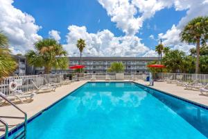 a swimming pool with chairs and palm trees and a building at Howard Johnson by Wyndham Orlando Lake Buena Vista South in Kissimmee