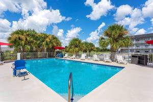a swimming pool with chairs and palm trees at Howard Johnson by Wyndham Orlando Lake Buena Vista South in Kissimmee