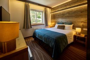 a bedroom with a bed with a wooden wall at Hôtel Le Grand Tétras in Font-Romeu