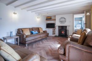 a living room with leather furniture and a fireplace at The Cross - 4 Bedroom Cottage - Llangennith in Llangennith