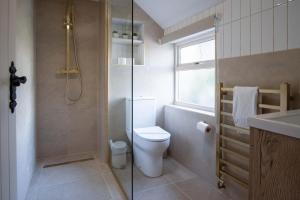 a bathroom with a toilet and a glass shower at The Cross - 4 Bedroom Cottage - Llangennith in Llangennith +47 photos