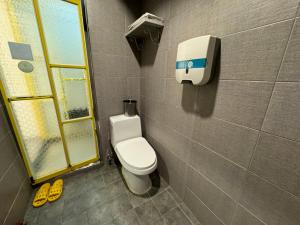 a bathroom with a toilet and a towel dispenser on the wall at Maison Seongsu KAN Hotel in Seoul