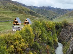 two houses on a hill next to a river at Cottage Caucasus in Ushguli
