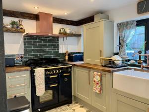 a kitchen with a stove top oven next to a sink at Old Cottage in Stratford upon Avon in Stratford-upon-Avon