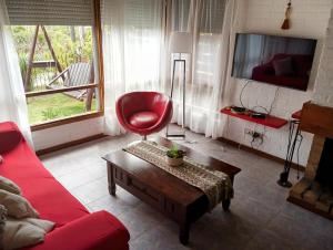 a living room with a red chair and a tv at Vistas del Cerro San Antonio in Piriápolis