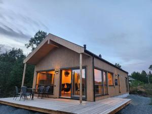 a house with a deck with a table and chairs at Nyoppført hytte med mulighet til å leie badestamp in Levanger