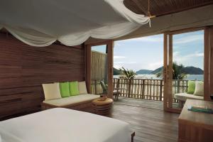 a bedroom with a balcony with a view of the ocean at Six Senses Con Dao - Turtle Island Paradise in Con Dao