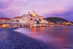a town on the shore of a body of water at night at Appartamento Arte in Imperia