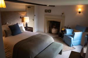 a bedroom with a bed and a couch and a chair at Charingworth Manor in Chipping Campden