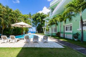 eine Terrasse mit Stühlen und einem Sonnenschirm neben einem Haus in der Unterkunft "Galeria Beach", Ocean front! in Sosúa