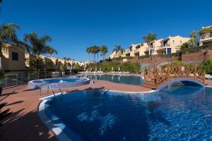 ein Resort mit zwei Pools, einer Brücke und Palmen in der Unterkunft Bahía Meloneras Relax in San Bartolomé de Tirajana